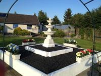 Anzio fontaine med kunstige planter rundt om i marmor krukker.